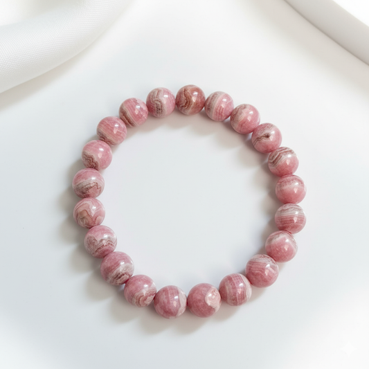 Polished Rhodochrosite gemstone bracelet with round beads on elastic band, displayed on neutral background