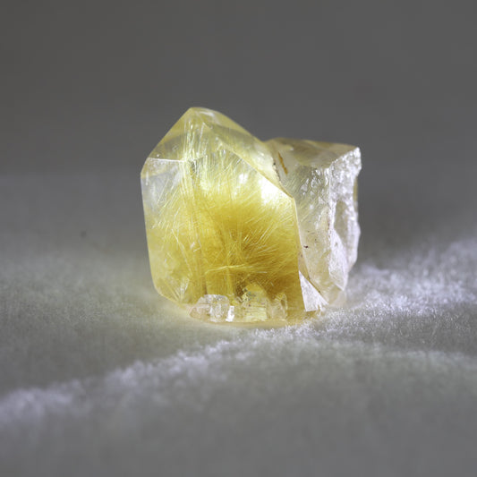 A small golden rutile quartz crystal cluster on a white background.