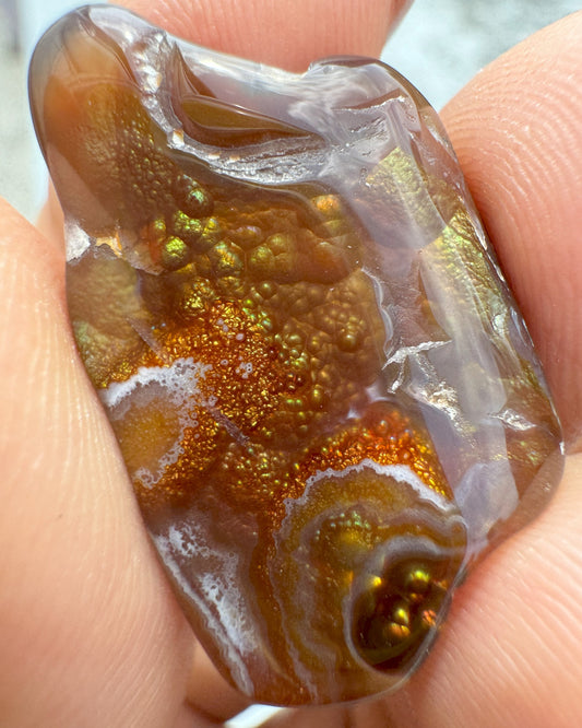 a natural, unpolished stone with fiery iridescent layers of red, orange, and brown, reflecting grounding and protective energy