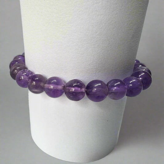 A purple amethyst bracelet displayed on a white stand.