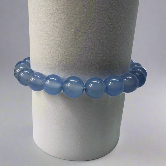 A blue chalcedony bracelet with 8mm round beads displayed on a cylindrical stand.