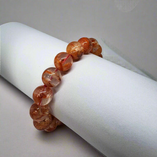 A bracelet made of polished star rose quartz beads, displayed on a white cylindrical object.