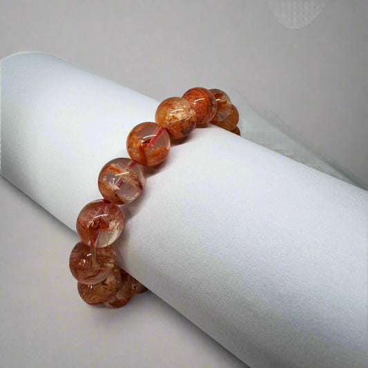 A bracelet made of star rose quartz beads displayed on a white cylindrical object.