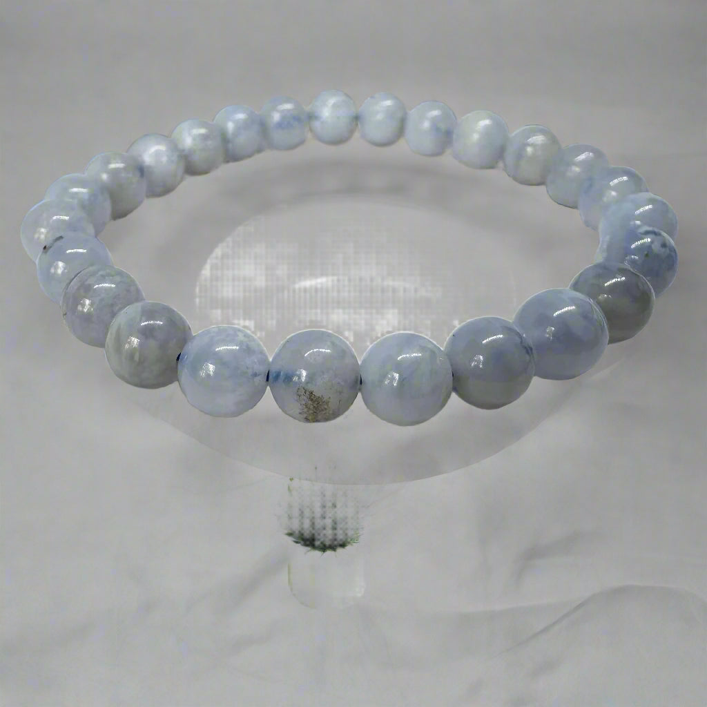 A blue lace agate bracelet with 8mm beads displayed on a clear stand.