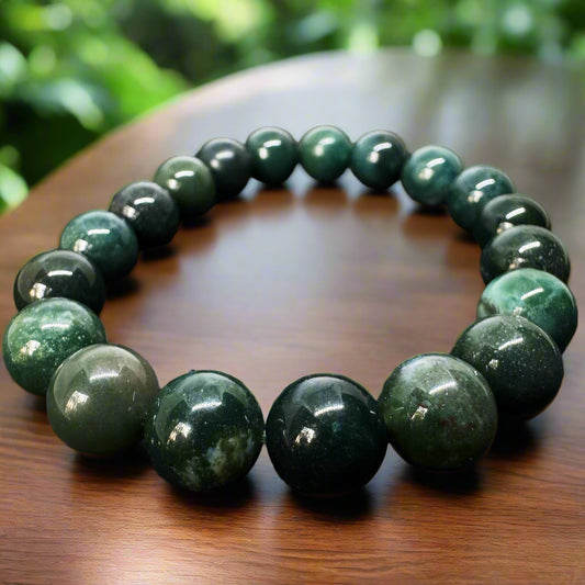 A Bloodstone Bracelet 10mm with beads displaying vibrant green color with reddish speckles, placed on a wooden surface.