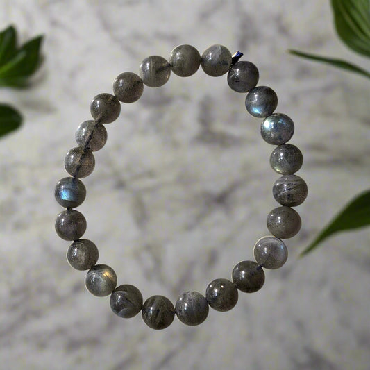 A bracelet with blue flashing labradorite beads, displayed on a marble surface.