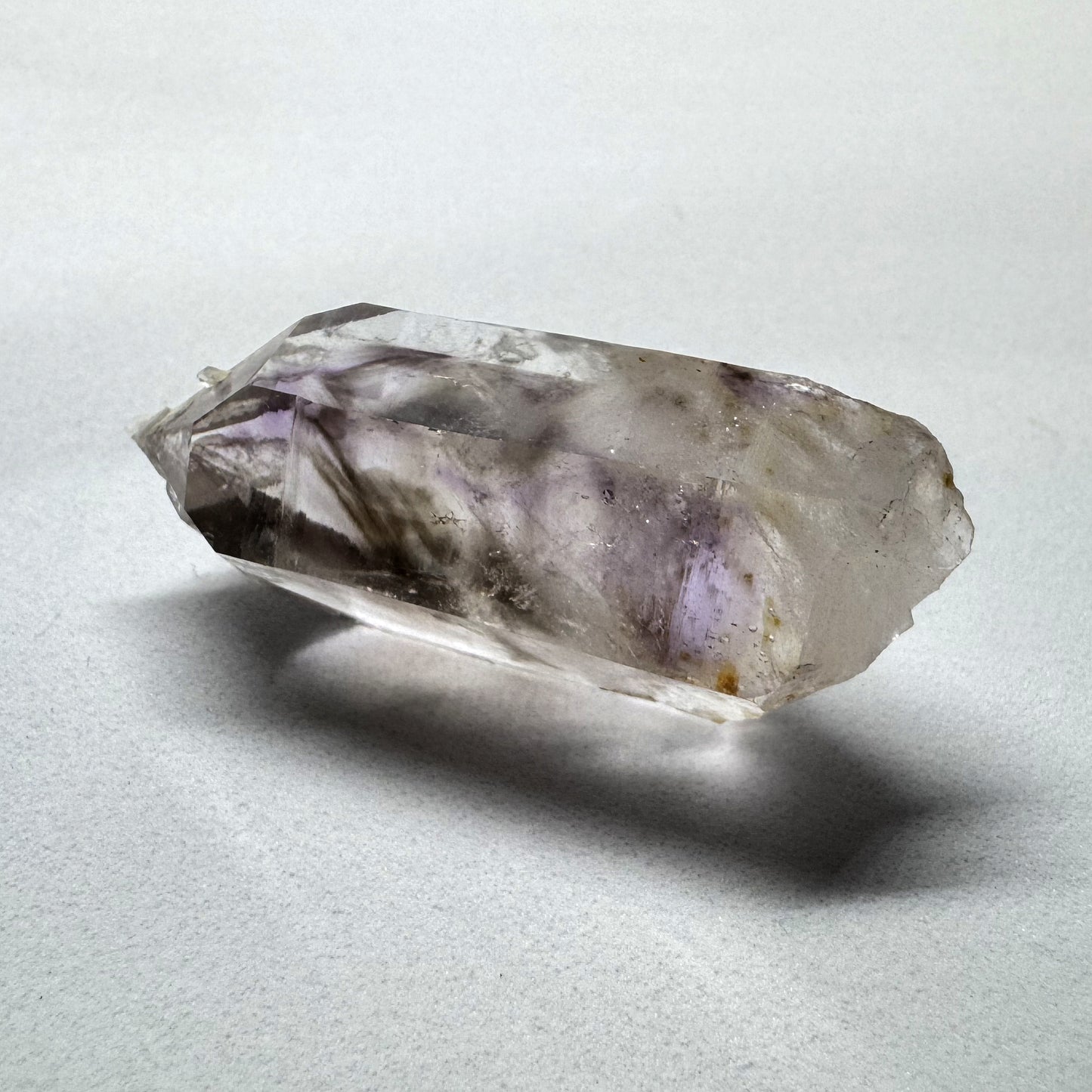 A polished Amethyst crystal with a Smokey Quartz cluster embedded in it, displaying a purple and brown color pattern.