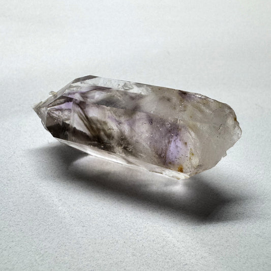 A polished Amethyst crystal with a Smokey Quartz cluster embedded in it, displaying a purple and brown color pattern.