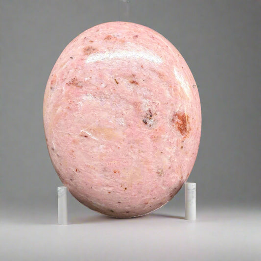 Polished Rhodonite palmstone showcasing pink and black marbled patterns, symbolizing emotional healing and balance