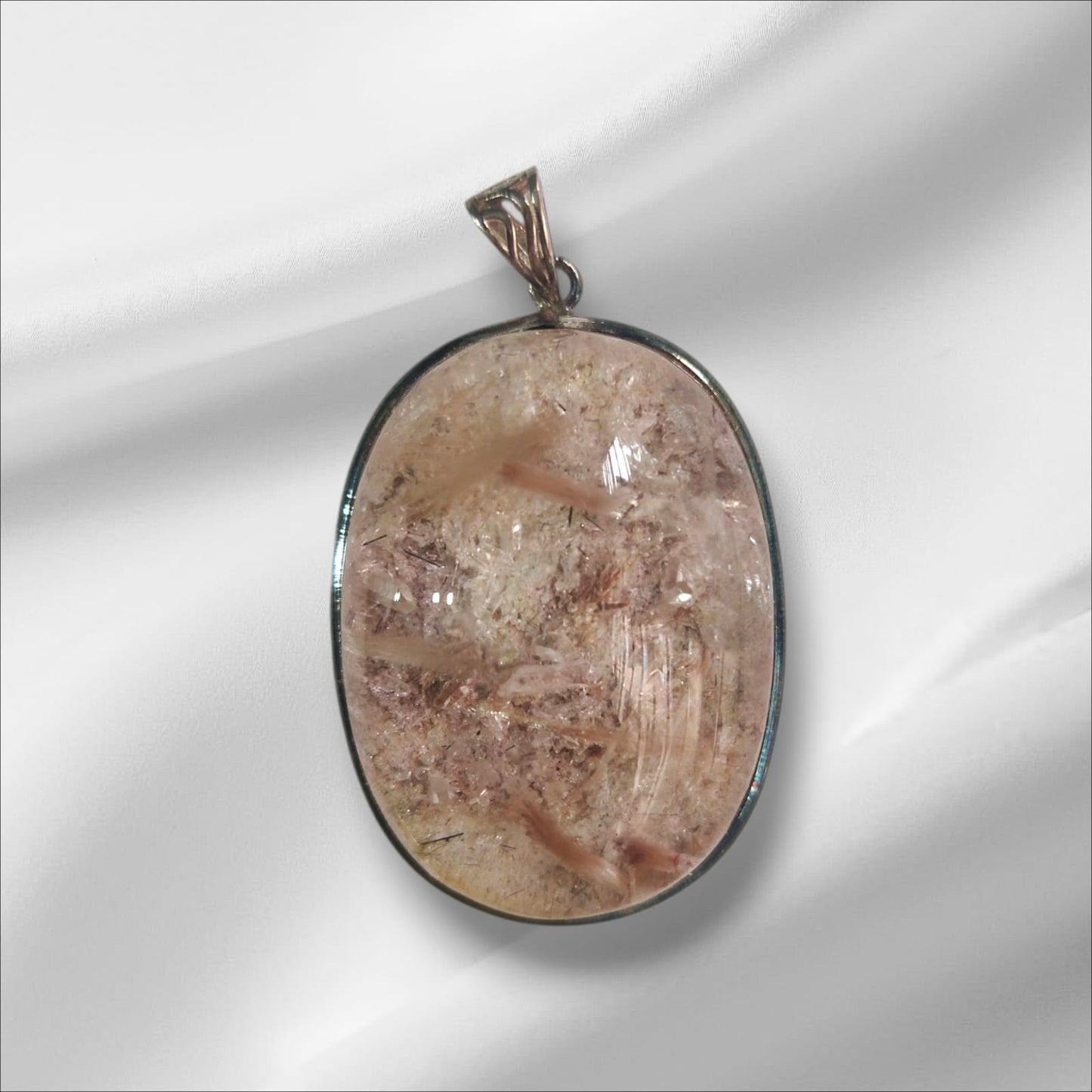 An oval-shaped pink rutile gemstone pendant set in a silver mounting, with a loop for a chain attachment at the top.