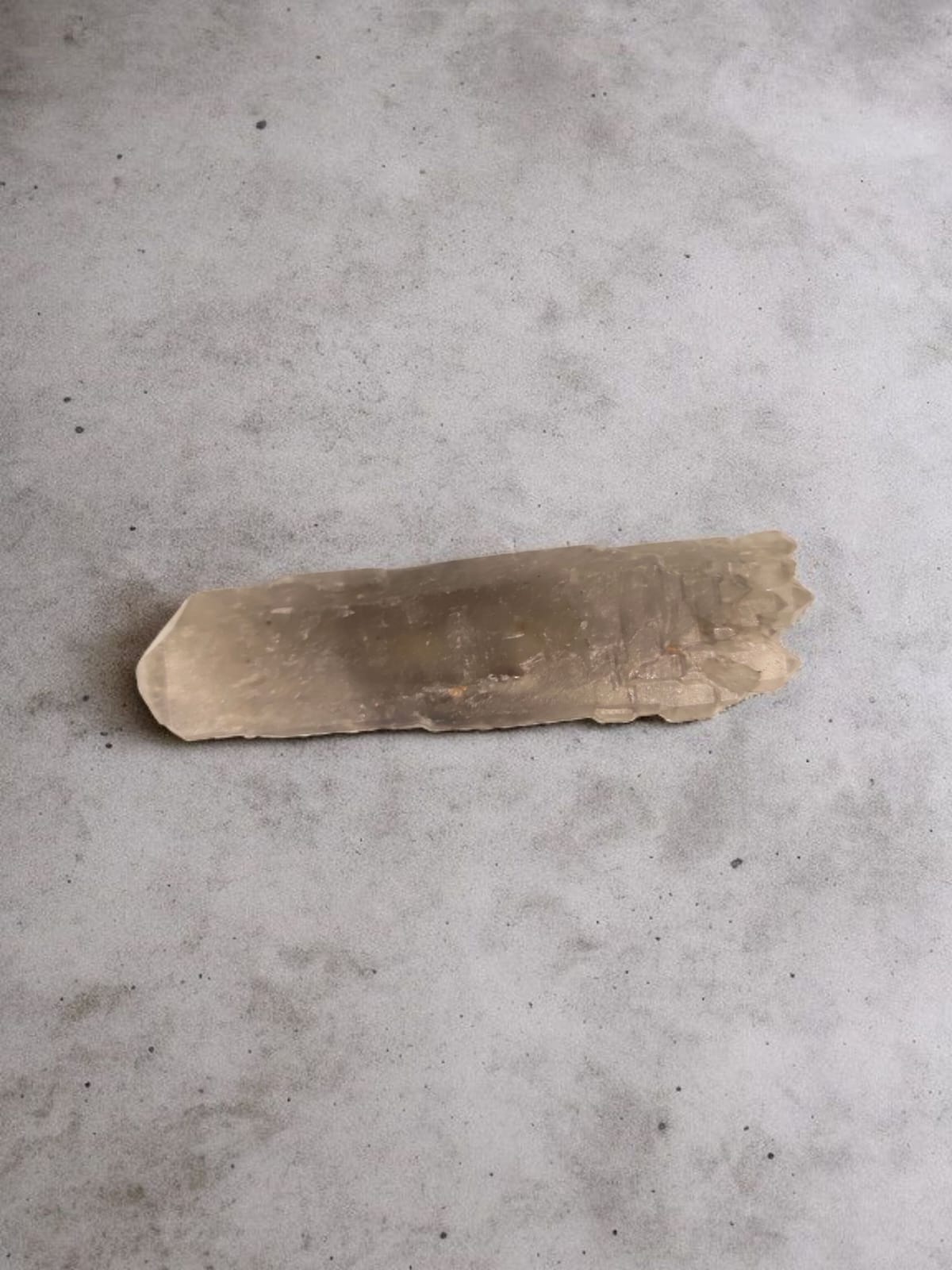 A smoky grey to dark brown quartz crystal cluster with natural luster, placed on a grey background.