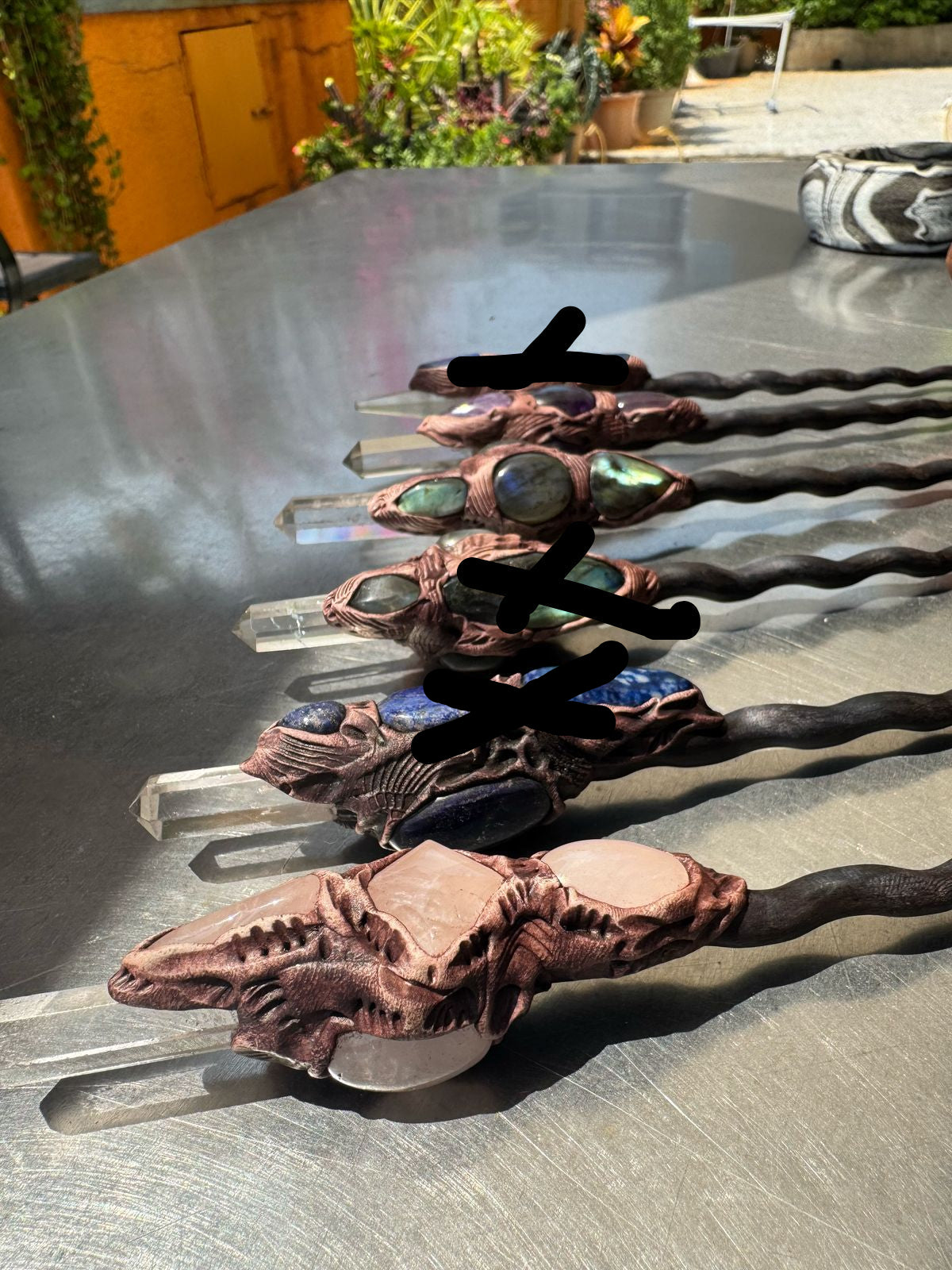 A selection of wooden wands with different crystal inlays, displayed on a table.