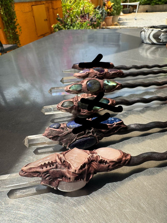 A selection of wooden wands with different crystal inlays, displayed on a table.