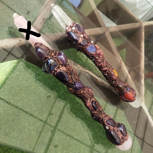 Decorative candles with intricate designs and gemstones on a reflective surface.