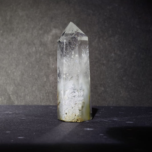 Clear crystal tower on a dark surface with a dark background