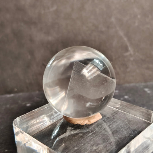 Clear crystal ball on a dark stone surface