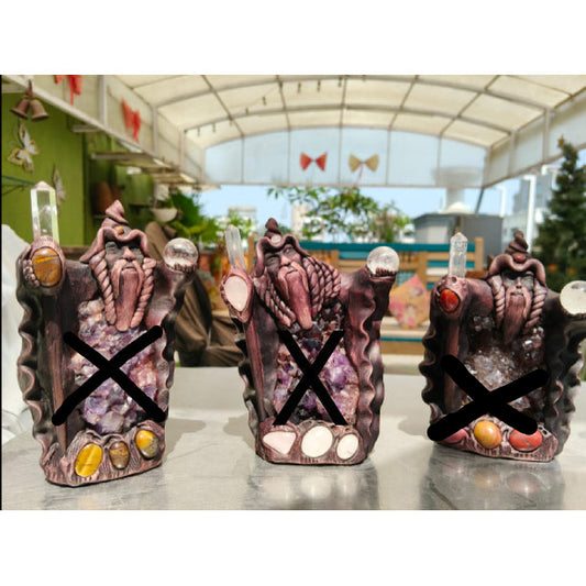 Three decorative stone-like figurines with colorful stones on a table in an indoor setting.